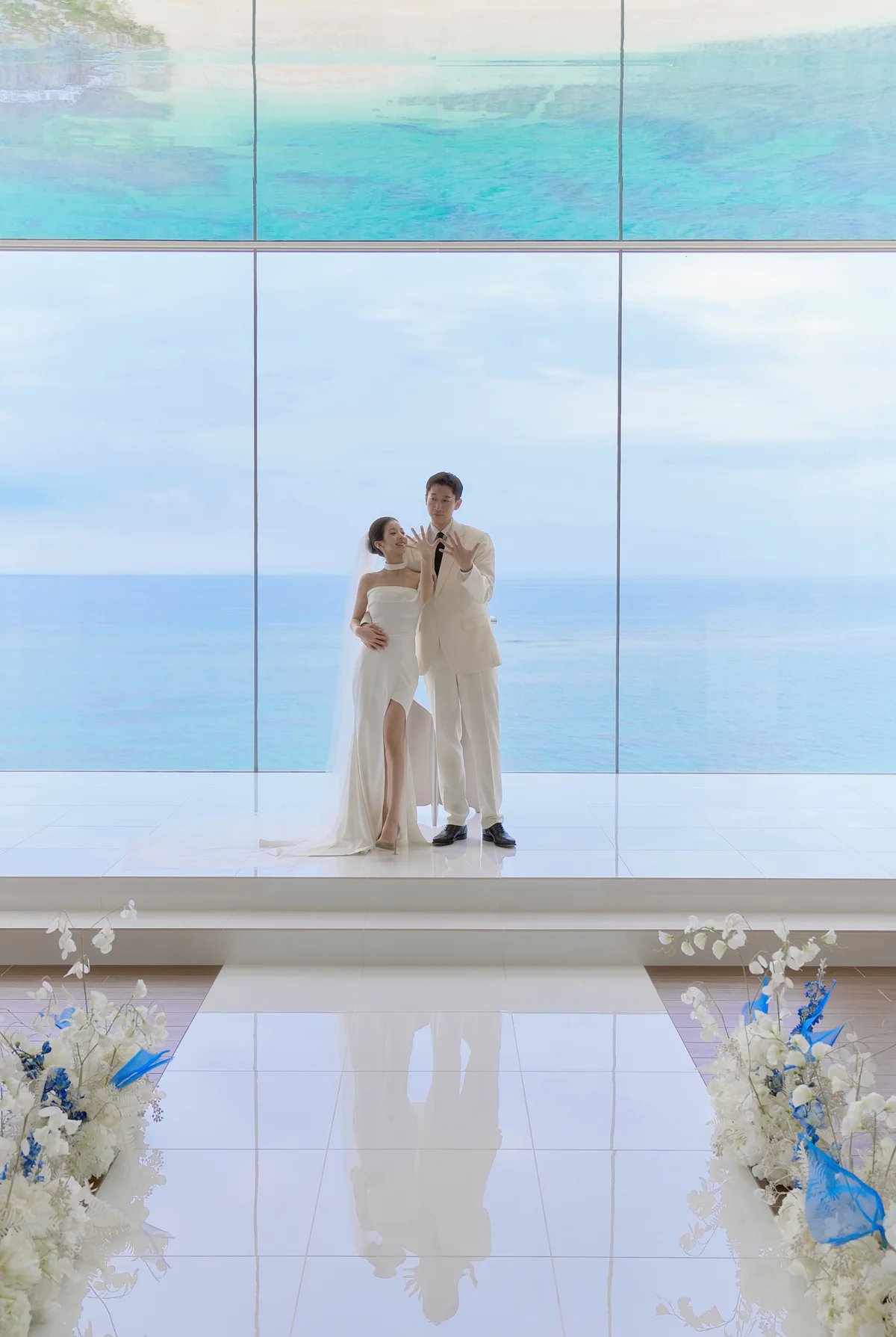 통유리 너머 바다를 배경으로 나란히 선 두 사람